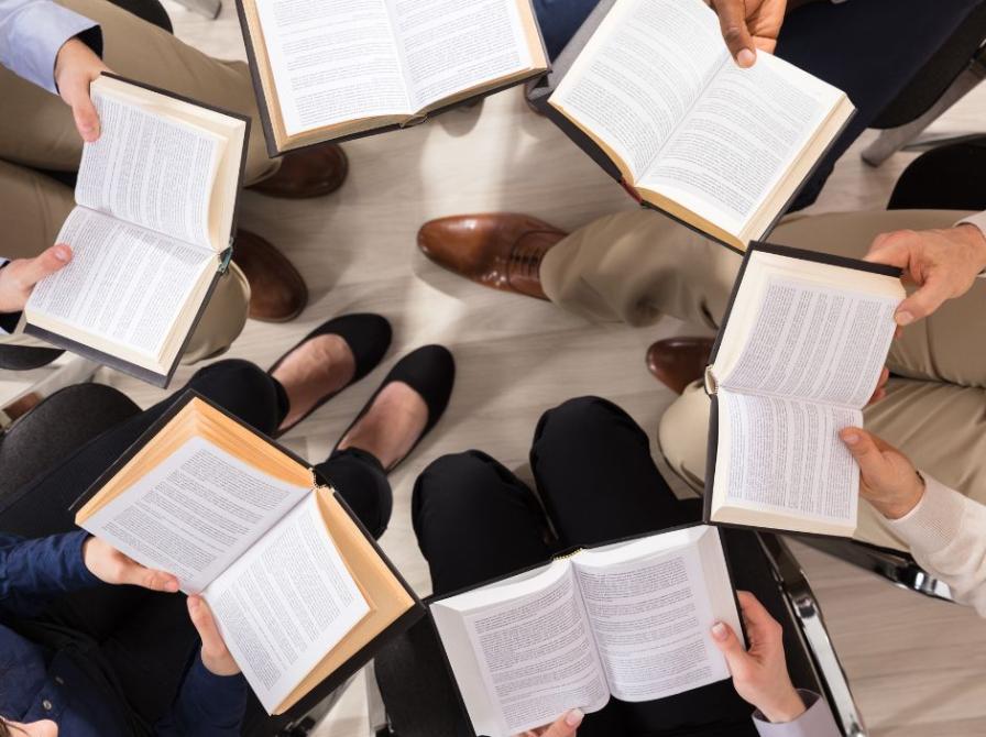 Folk i rundkreds med bog i hånden